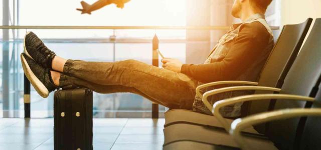 A man sitting on a bench watching a plane take off